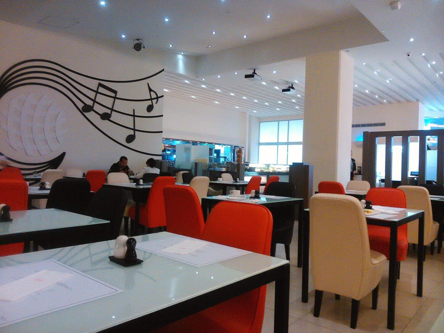 Sala de restaurante com mesas, cadeiras e balcão ao fundo